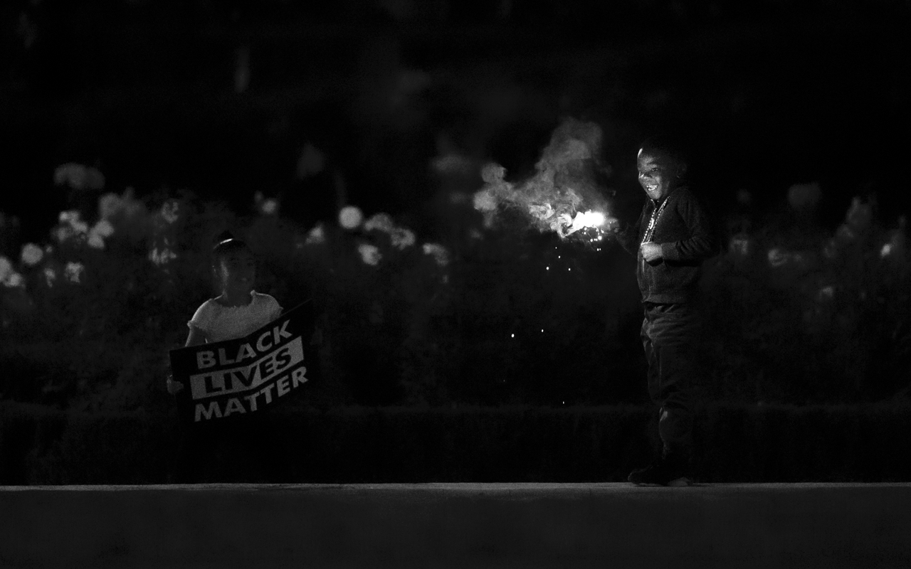 Photo caption: Two siblings—one holding a sparkler and the other a sign that reads “Black Lives Matter”—stand in solidarity at a violin vigil in Portland for Elijah McClain. Photo credit: Fred Joe Photo